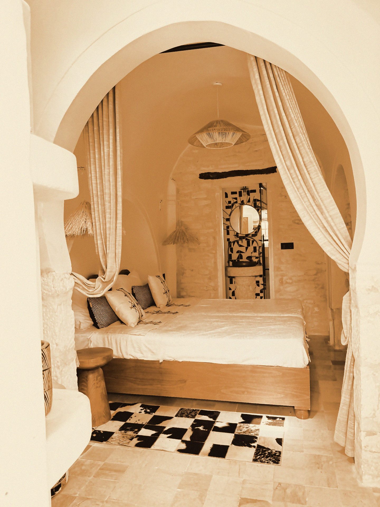 A whitewashed room with an arched alcove and canopy bed